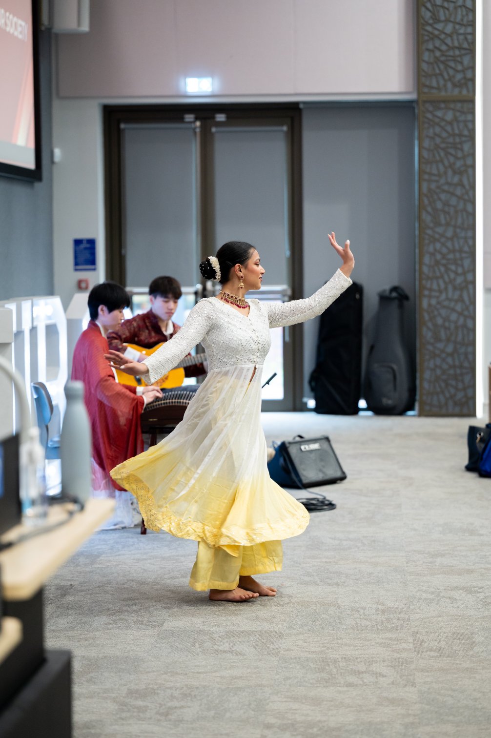 Indian classical dance performance, with Chinese musicians playing guzheng and guitar behind